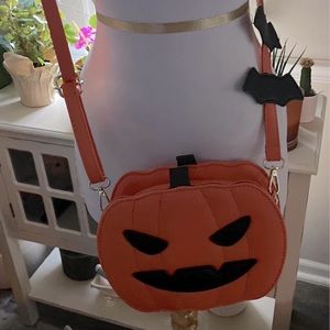 Orange pumpkin cross body handbag with bats on strap.